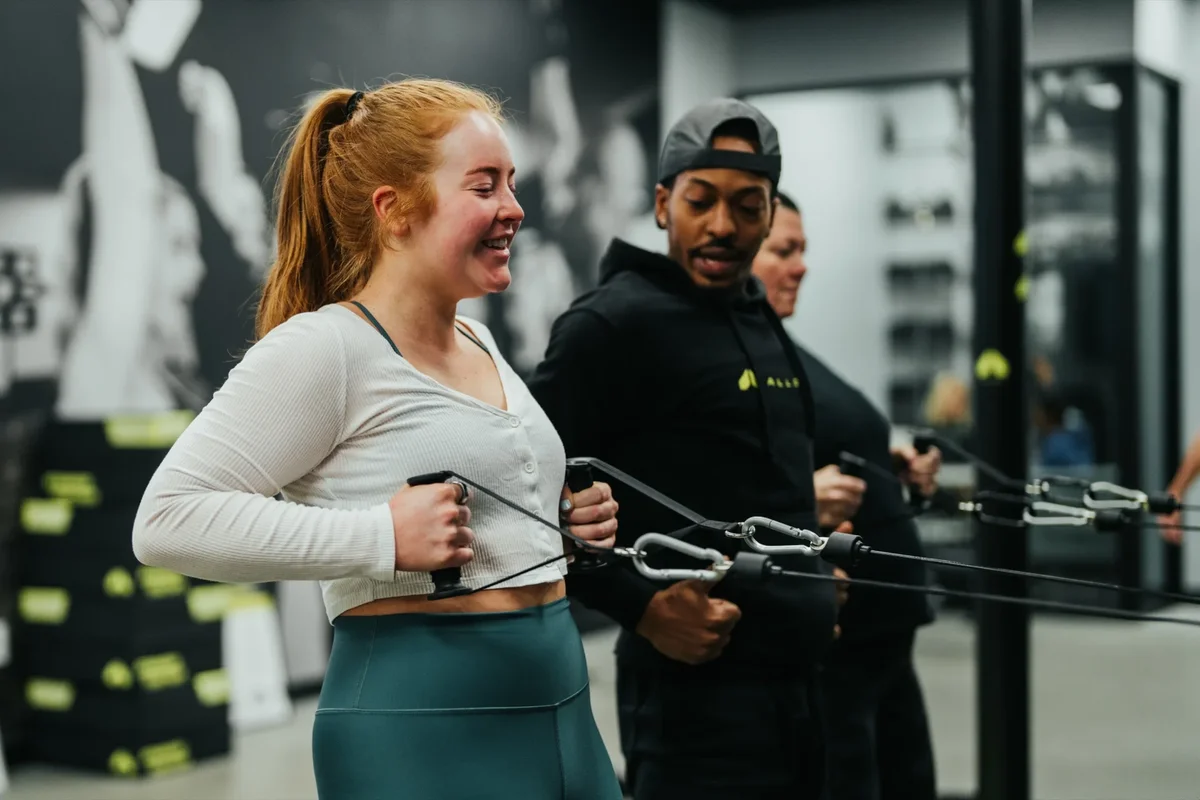 A coach works through a cable exercise with a member at an Alloy Personal Training studio